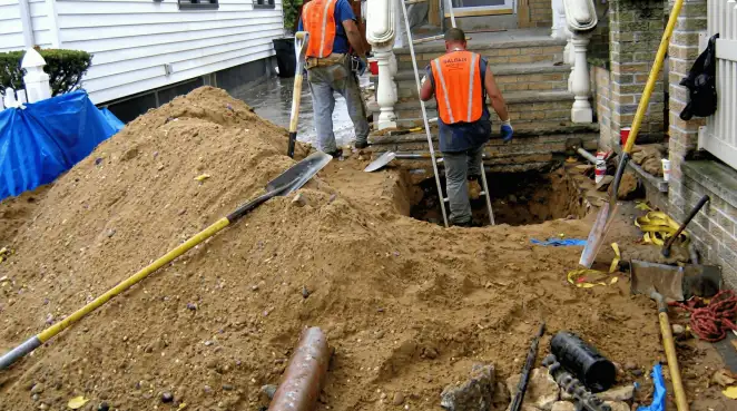 Contractors performing foundation protection and exterior drainage excavation near residential home steps in Jackson, MS